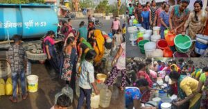 group of people standing around a water tank to take water