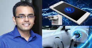 Man with blue shirt and glasses beside a car anda cell phone.